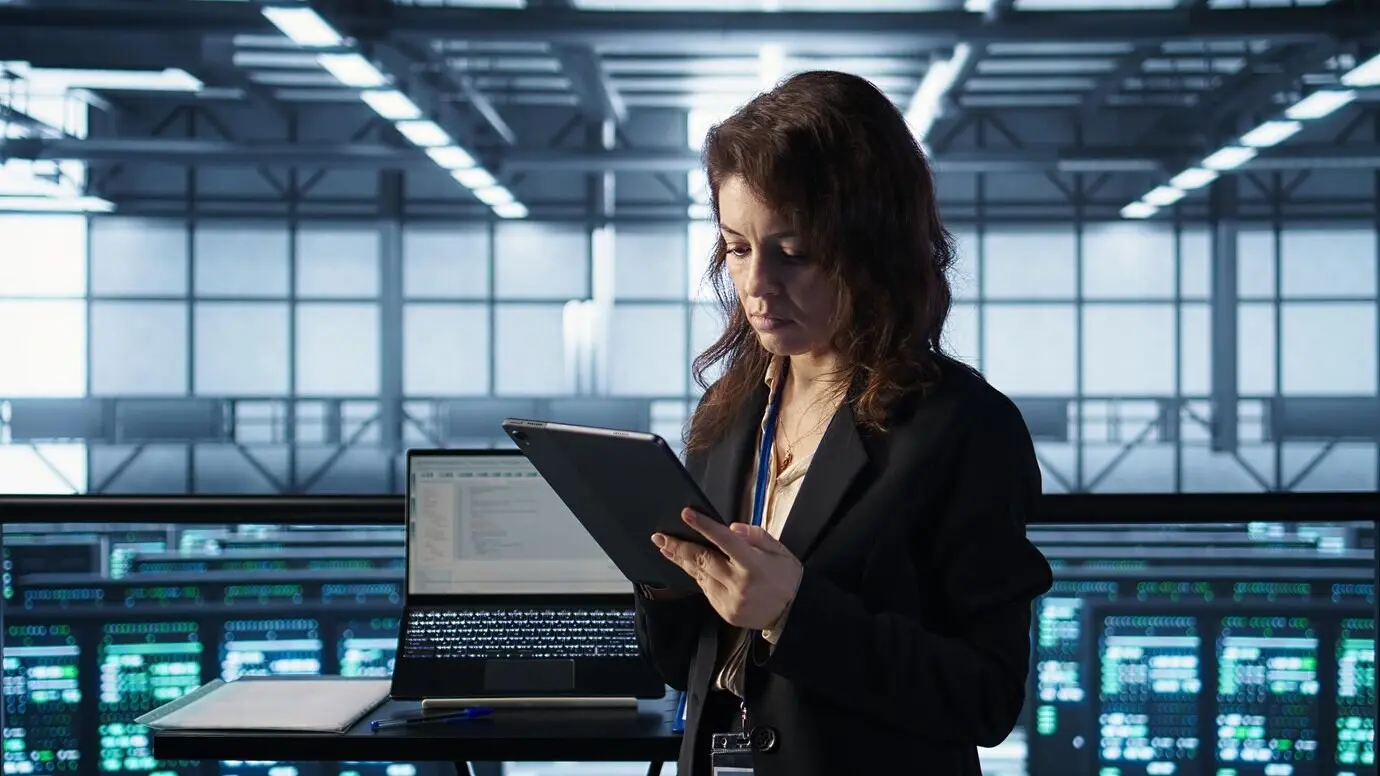Técnico en un centro de datos que utiliza tecnología de IA en una tableta.